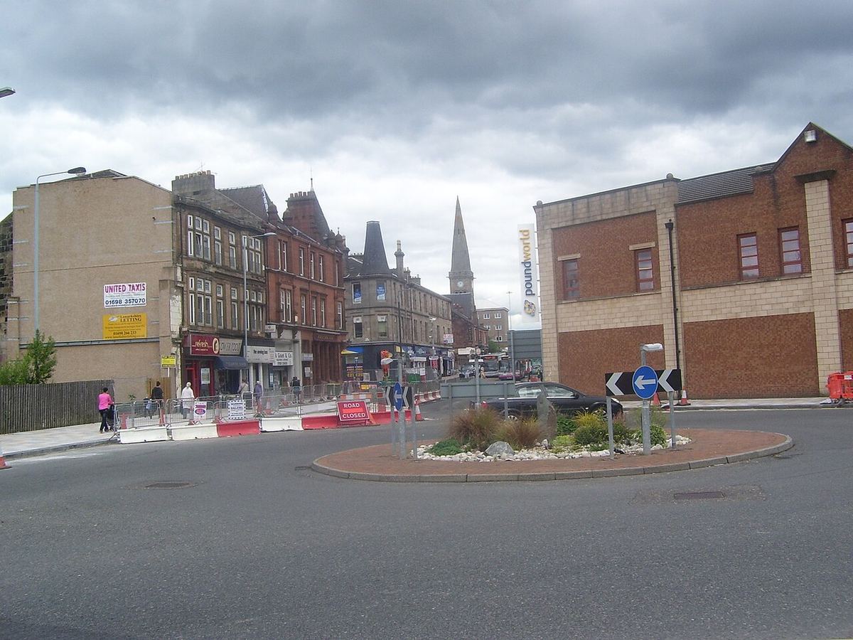 Roundabout in Motherwell town centre, with shops and a church spire behind